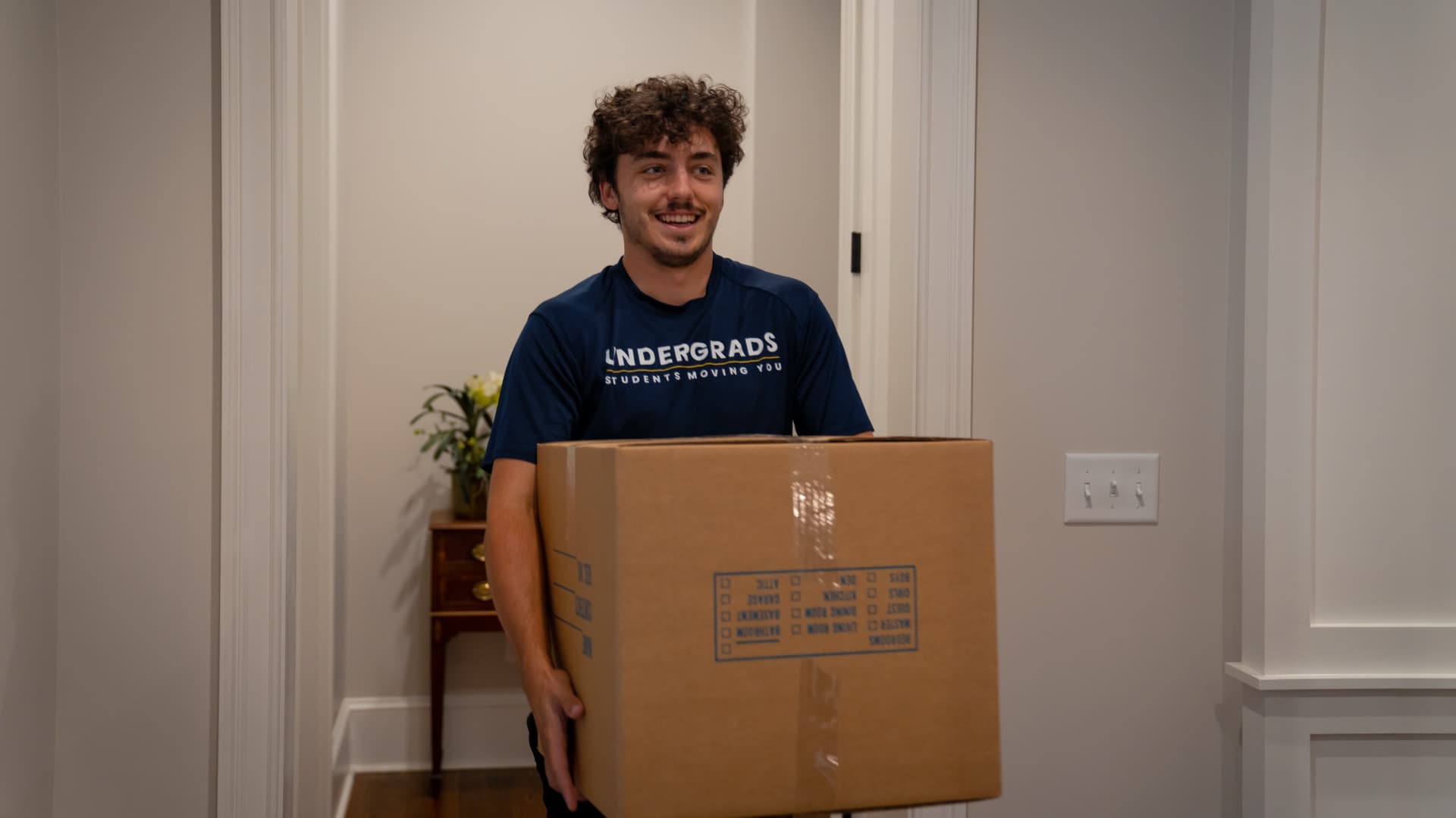 Undergrads crew member smiling while carrying a box — the move always happens