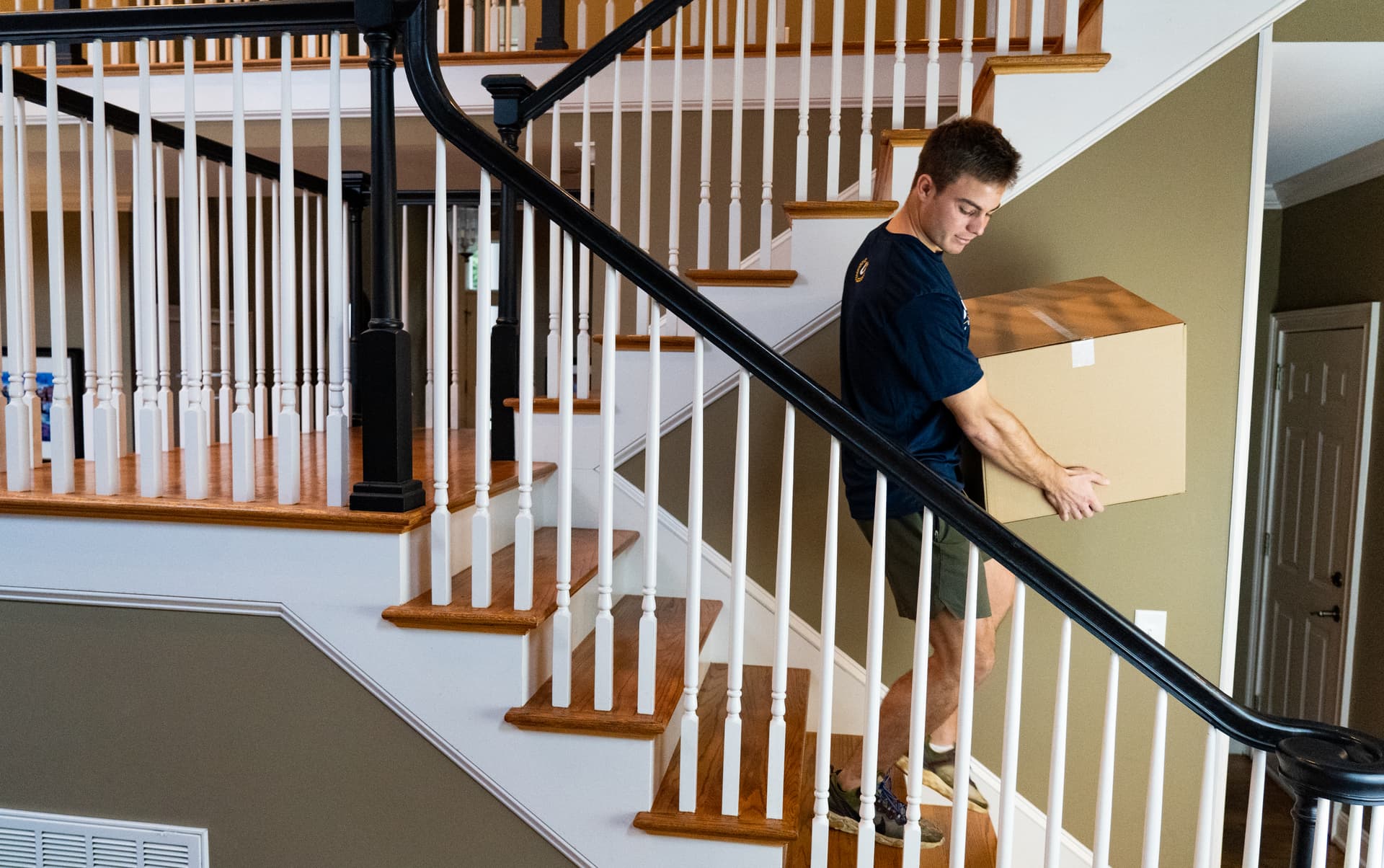 Undergrads crew member carrying a box down a staircase